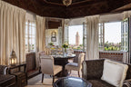 Luxury hotel dining room at La Mamounia Marrakech featuring carved wooden ceiling, tiled walls, round table set for tea, plush chairs