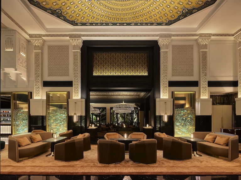 La Mamounia Marrakech elegant hotel lobby with beige and brown sofas, ornate pillars, intricate ceiling design, and ambient lighting