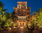 La Mamounia Marrakech luxury hotel exterior at night with warm lighting, Moroccan architecture, and outdoor dining area surrounded by lush greenery