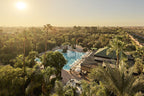 La Mamounia Marrakech luxury hotel with large blue swimming pool, white sun loungers, and lush green palm trees under warm sunlight