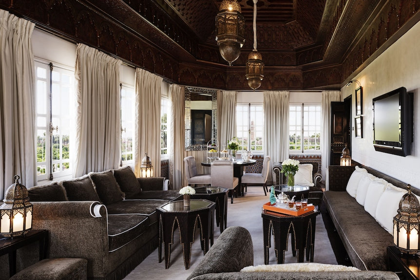La Mamounia Marrakech living room with traditional wooden ceiling, white curtains, dark brown sofas, and ornate lanterns