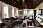 La Mamounia Marrakech living room with traditional wooden ceiling, white curtains, dark brown sofas, and ornate lanterns