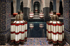 La Mamounia Marrakech Moroccan lanterns with red and white glass panels surrounding a reflective dark blue tiled pool and intricate mosaic columns
