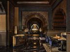 La Mamounia Marrakech restaurant interior with dark marble floors, intricate archways, warm lighting, and elegant seating
