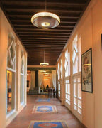 Le Berbere Palace Ouarzazate hotel corridor with terracotta tile flooring, wooden beamed ceiling, large windows, and hanging circular light fixtures