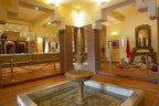 Le Berbere Palace Ouarzazate hotel interior with ornate tiled walls, central stone fountain, and warm yellow lighting