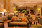 Le Berbere Palace Ouarzazate hotel lobby featuring beige and orange cushions, terracotta tiled floor, warm lighting, and floral centerpiece