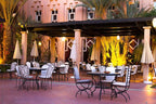 Le Berbere Palace Ouarzazate outdoor dining area with wrought iron chairs, round tables, beige umbrellas and warm lighting
