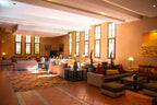Le Berbere Palace Ouarzazate spacious hotel lounge with terracotta floor tiles, beige sofas, colorful cushions, and large windows
