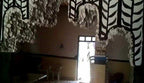Interior of Le Gout Du Sahara Hostel featuring dark walls with white tribal decorative patterns and a doorway with light streaming in.