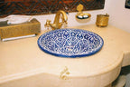 Luxury Camp Chebbi blue and white ceramic sink with intricate floral patterns and a vintage brass faucet on beige countertop