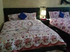 Maison Riad Tamarighte bedroom with two floral patterned beds, purple pillows, and towel swans on one bed