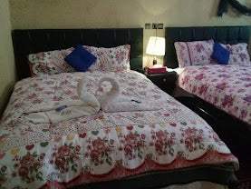Maison Riad Tamarighte bedroom with two floral patterned beds, purple pillows, and towel swans on one bed