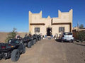Maison Riad Tamarighte beige stucco building with traditional Moroccan architectural details and outdoor parked quad bikes.
