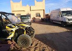 Maison Riad Tamarighte beige sandstone building with traditional Moroccan design, parked white vans and an off-road buggy outside