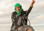 Marrakech Agafay Desert camel ride with smiling rider in green headscarf and patterned black robe