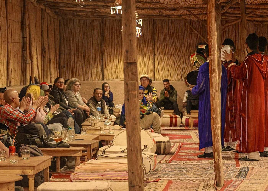 Marrakech Agafay Desert dinner show with seated guests and performers in colorful traditional Moroccan robes