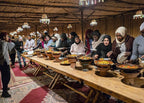 Marrakech Agafay Desert Moroccan dinner served in a rustic Berber-style camp with guests and tagine dishes
