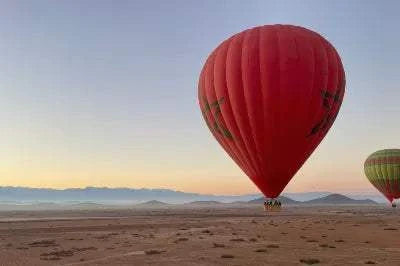 Marrakech by air hot air balloon with a large red envelope landing on a desert plain