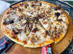 Thin-crust pizza with melted cheese, ground meat, and herbs on a wooden board, showcasing a Merzouga Cooking Class dish.