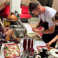 Merzouga Cooking Class showing a group preparing traditional Moroccan dishes on patterned trays at a kitchen table.