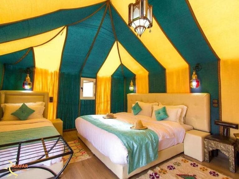 Merzouga Desert Camp interior with two beds, teal and yellow fabric walls and ceiling, teal cushions and a hanging lantern