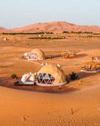 Merzouga Glamping Camp with beige geodesic dome tents featuring glass windows set in the Sahara Desert sand dunes.