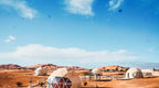 Merzouga Glamping Camp featuring white geodesic dome tents with transparent triangular windows set in sandy desert dunes.