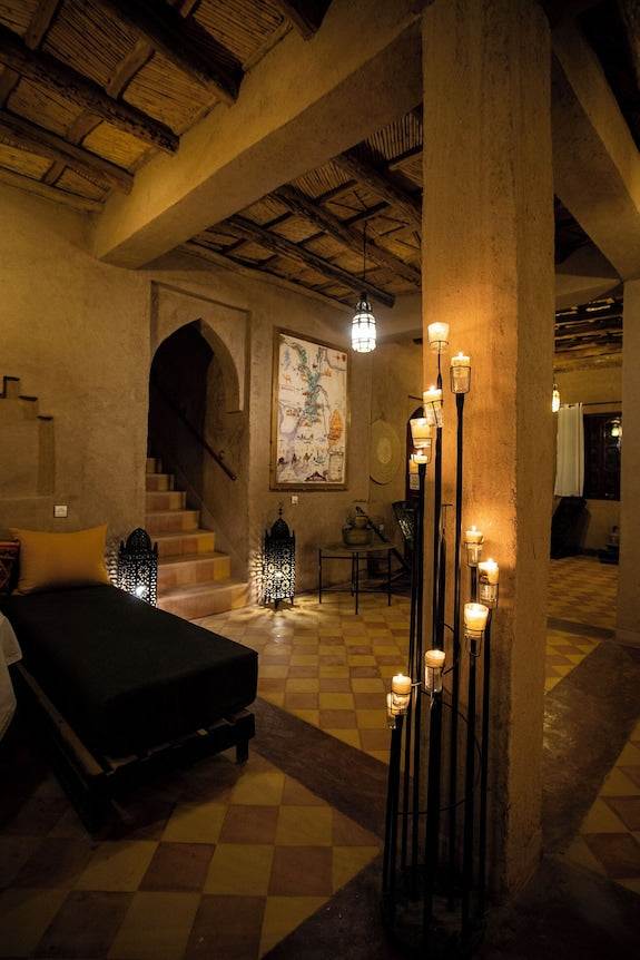 merzouga hotel kanz erremal cozy rustic interior with warm earthen tones, tiled floor, decorative lanterns, and ambient candle lighting