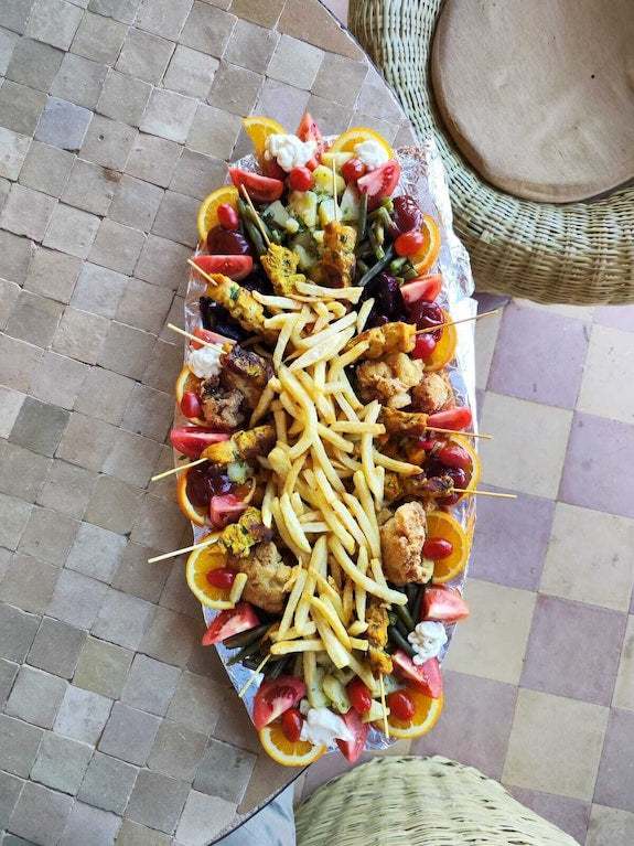 Platter of assorted fried appetizers including chicken, mixed vegetables, and French fries on a silver tray at Merzouga hotel kanz Erremal