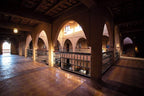 Interior view of Merzouga hotel kanz Erremal with terracotta tiled floor, archways, traditional railing, and rustic decor