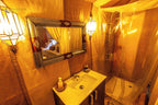 Merzouga Luxury Camp bathroom with wooden sink cabinet, patterned framed mirror, lantern lighting, and plastic-covered shower