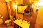 Merzouga Luxury Camp bathroom with warm-toned fabric walls, ornate framed mirror, white toilet, sink, and soft lighting
