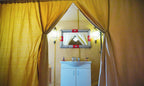 Merzouga Luxury Camp tent interior featuring beige fabric walls, a white vanity cabinet, decorative mirror with red accents, and lantern-style lights