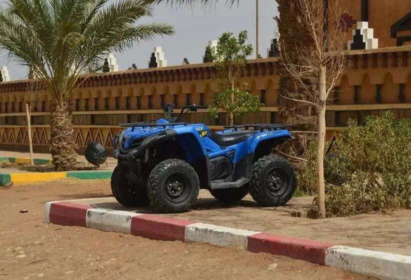 Blue Merzouga Quad Bike with rugged black tires parked next to palm trees and a traditional decorative wall