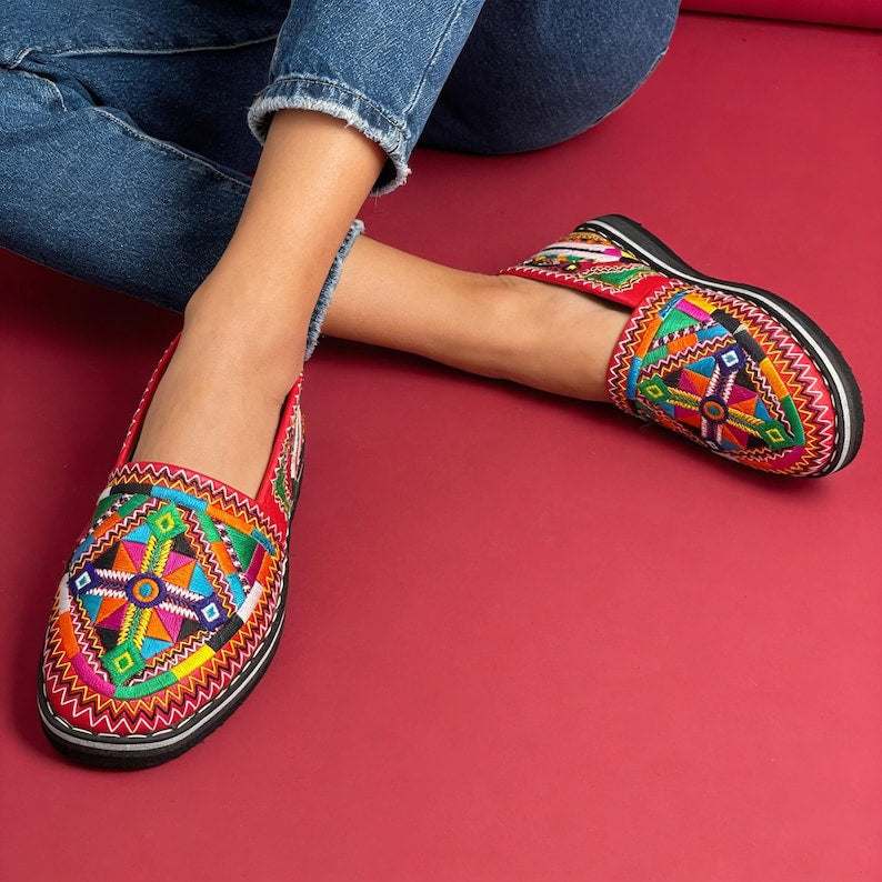 Moroccan Berber leather moccasins with colorful embroidered geometric patterns and black soles, perfect for Merzouga Shopping.