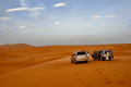 4x4 SUVs in silver and black parked on golden sand dunes with footsteps nearby during Merzouga to Zagora desert tour