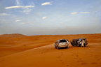 4x4 SUVs in silver and black parked on golden sand dunes with footsteps nearby during Merzouga to Zagora desert tour