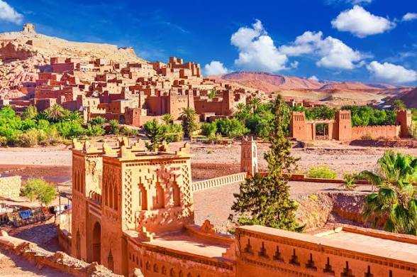 Traditional Moroccan desert mudbrick buildings with intricate patterns under a blue sky, highlighting the Merzouga Tour Guide experience.