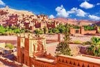 Traditional Moroccan desert mudbrick buildings with intricate patterns under a blue sky, highlighting the Merzouga Tour Guide experience.