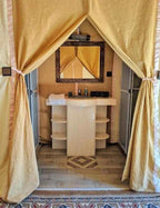 Merzouga VIP Luxury Camp bathroom area with beige curtains, a cream vanity sink, tiled floor, and a framed mirror