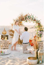 Merzouga VIP Luxury Camp romantic desert proposal setup with floral arch, golden lanterns, and decorative rugs on sand