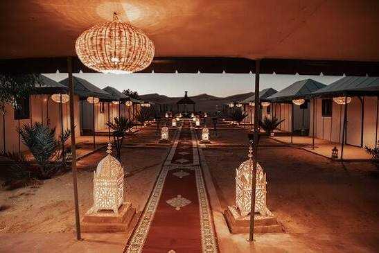 Moonlight luxury Desert Camp with illuminated ornate lanterns, traditional carpets, and luxury tents at dusk in desert