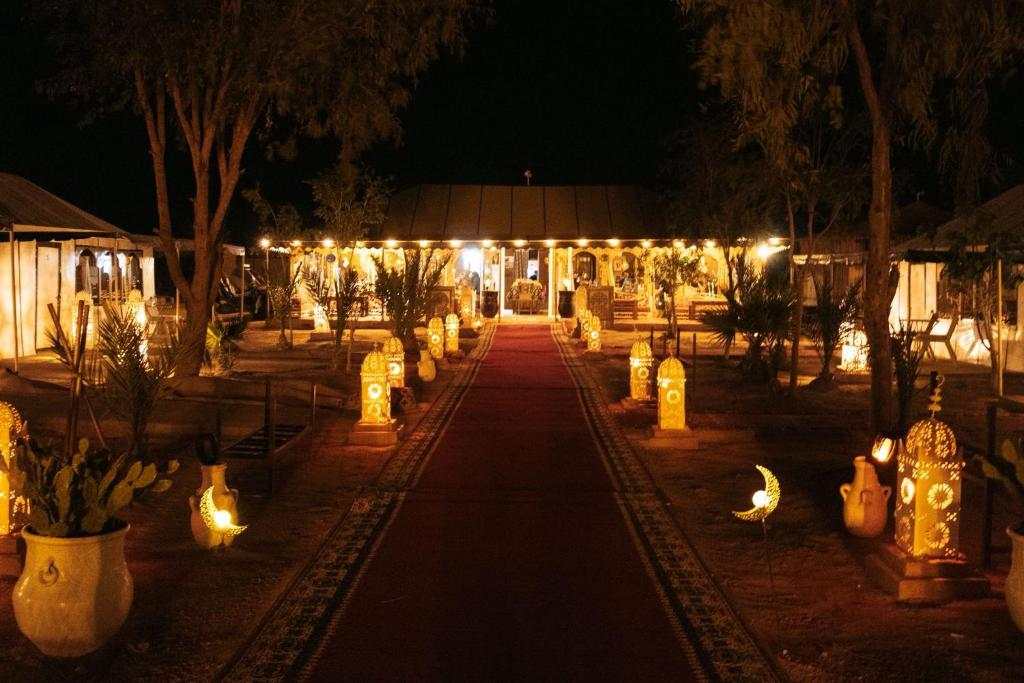 Moonlight luxury Desert Camp illuminated at night with decorative lanterns along a red carpet path surrounded by desert plants