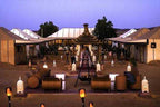Moonlight luxury Desert Camp featuring large beige canvas tents with peaked roofs, outdoor seating, and Moroccan lanterns at dusk