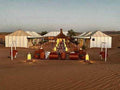 Moonlight luxury Desert Camp features spacious white canvas tents on a sandy desert landscape with traditional lanterns and seating areas.