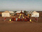 Moonlight luxury Desert Camp features spacious white canvas tents on a sandy desert landscape with traditional lanterns and seating areas.