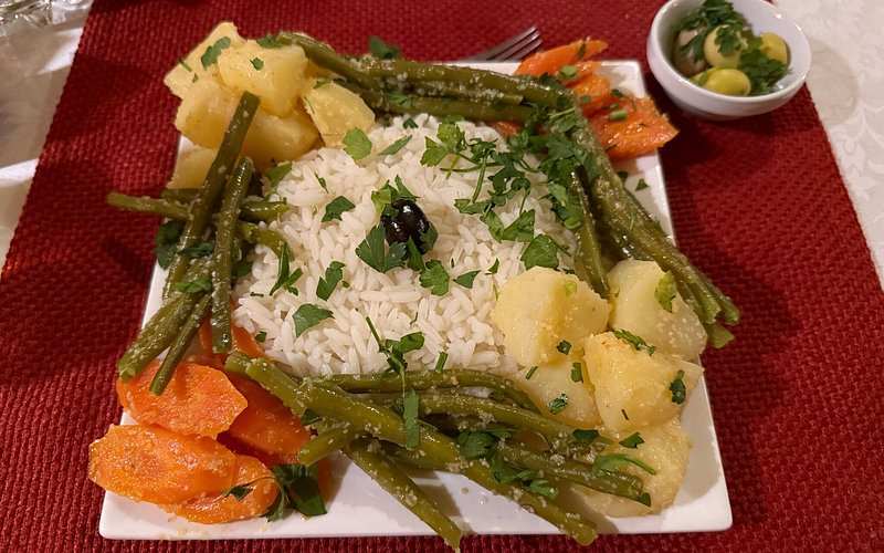 Plate of Moroccan cuisine with white rice garnished with parsley, green beans, carrots, and potatoes at Moonlight luxury Desert Camp