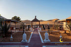 Moonlight luxury Desert Camp outdoor seating area with beige luxury tents, ornate white lanterns, and sand dunes in the background