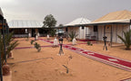 Moonlight luxury Desert Camp featuring white and beige luxury tents with metal roofs on sandy terrain and red patterned carpets